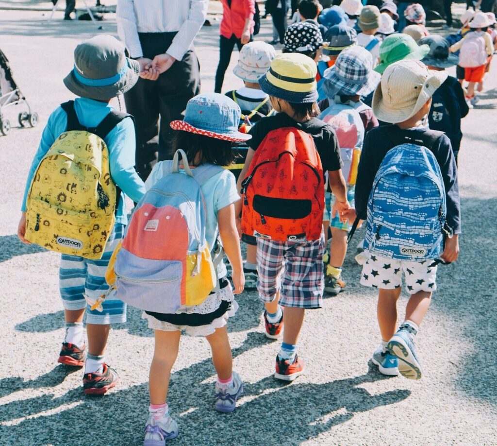 Photo by note thanun group of people wearing white and orange backpacks walking on gray concrete pavement during daytime